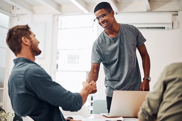 Two smiling men shake hands